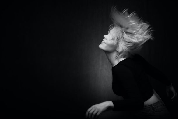 woman swooshing her hair around on a black background