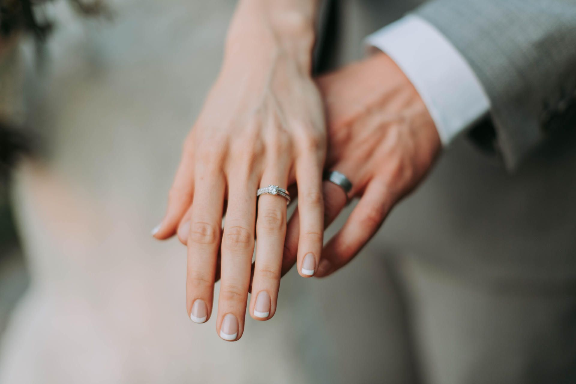 married couple standing next to each other holding out hands with wedding rings on