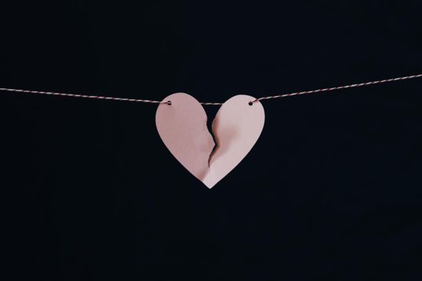 a torn paper heart over a black background on a string
