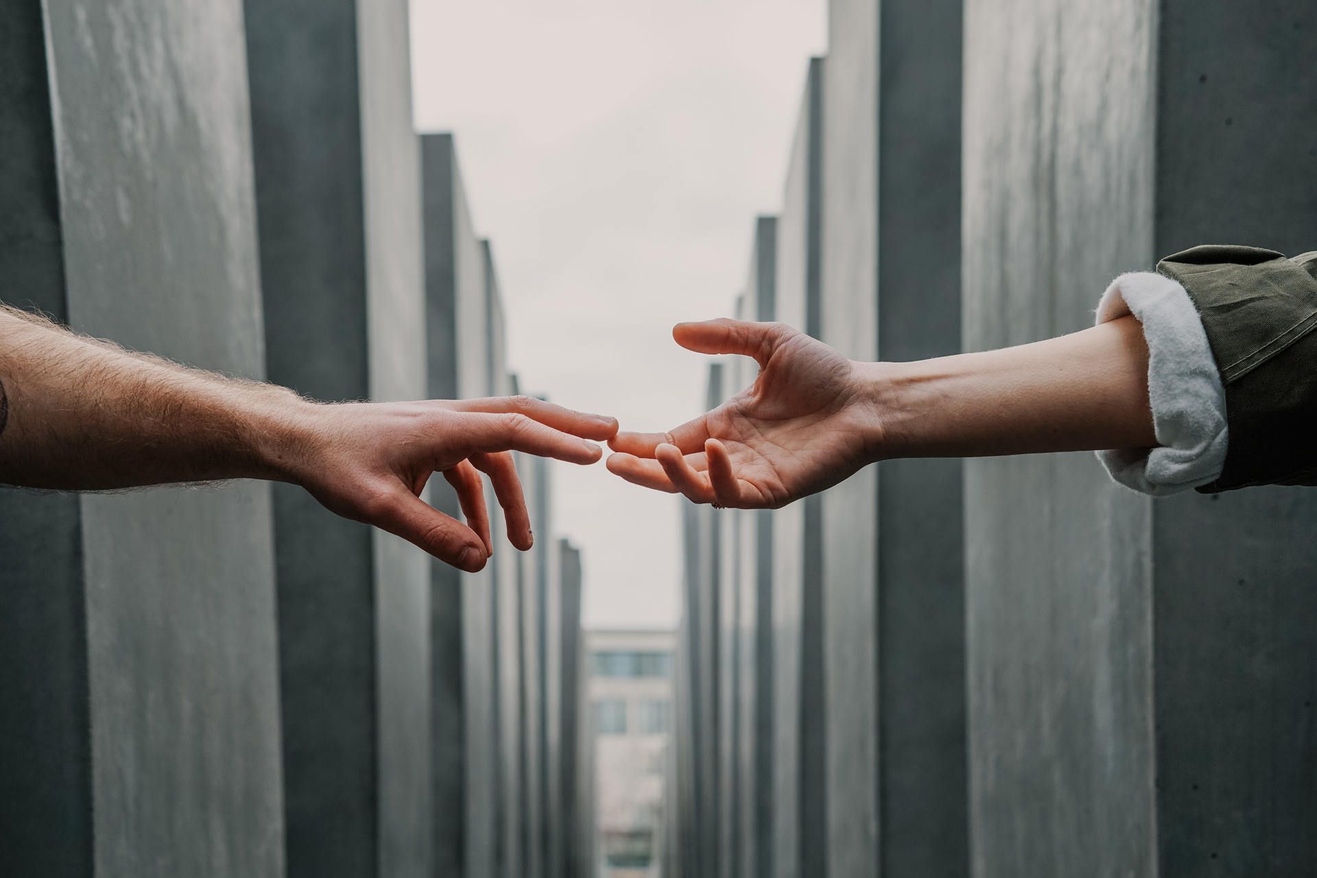 two people reaching out to touch hands outside