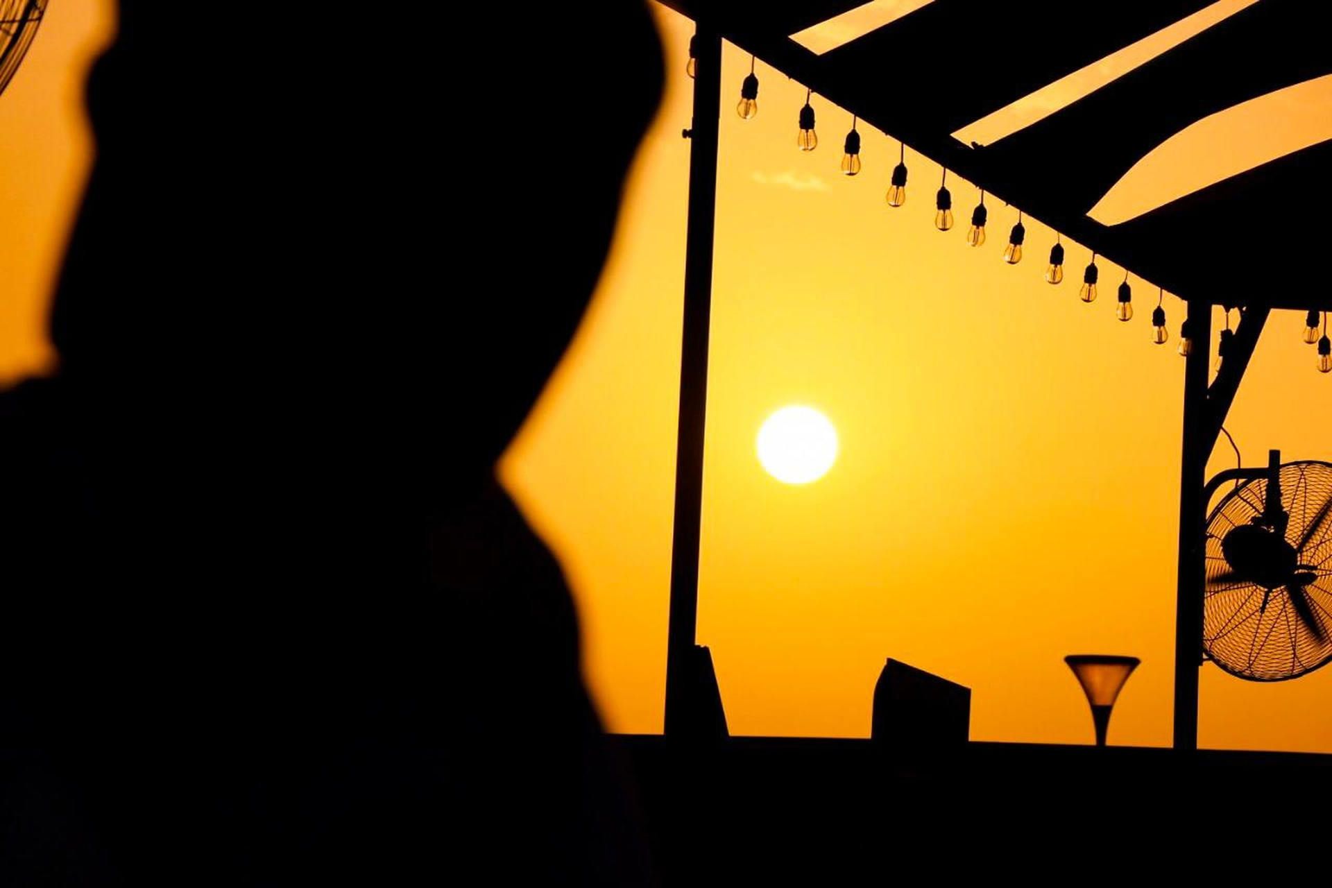 Person with a hat outside looking at the sun with a yellow sky