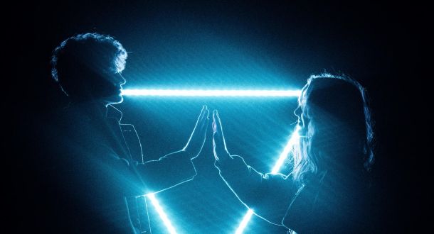 couple touching hands in dark with blue lasers
