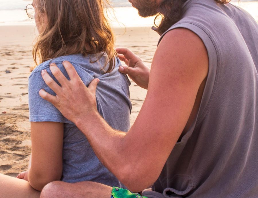 man massaging a woman's back outdoors on the beach