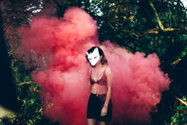 woman outside with a mask with red smoke around her